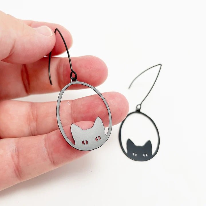 DENZ Mini Black Cat dangles in black, held by hand