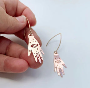 DENZ Mini Magic hand dangles in rose gold, held by hand