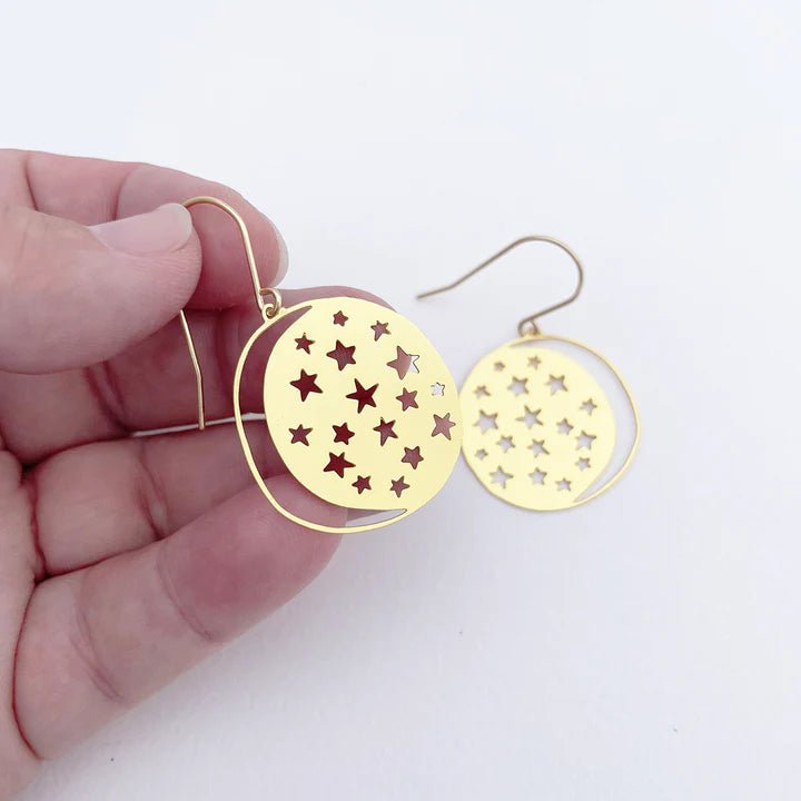 DENZ Mini Moonstars in Gold earrings, held by hand