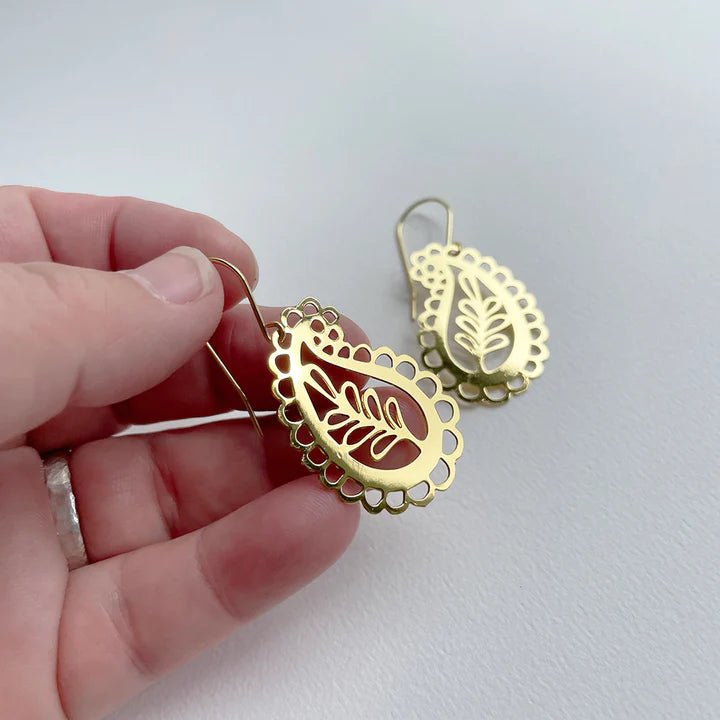 DENZ Mini Paisley dangles in gold, held by hand