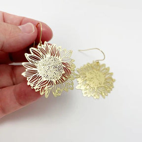DENZ Mini Sunflower dangles in gold, held by hand