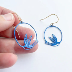 DENZ Mini Swallow dangles in blue, held by hand