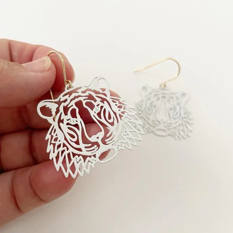 DENZ Mini Tigers in white earrings, held by hand