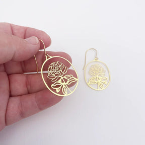 DENZ Mini Waratahs in Gold earrings, held by hand