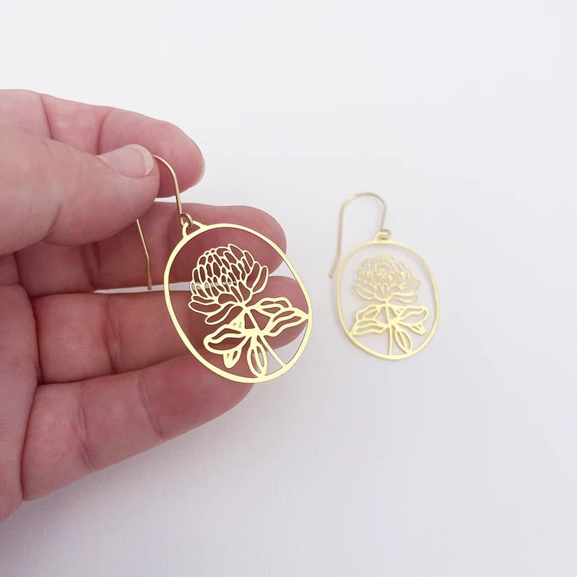 DENZ Mini Waratahs in Gold earrings, held by hand
