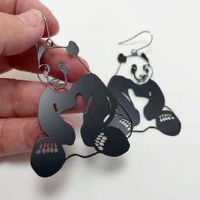 DENZ Pandas in black earrings, held by hand
