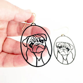 DENZ Pug Dangles in Black earrings, held by hand