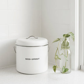 Seed & Sprout mushroom kitchen compost bin styled on a white speckled countertop next to a glass vase with a pothos cutting.