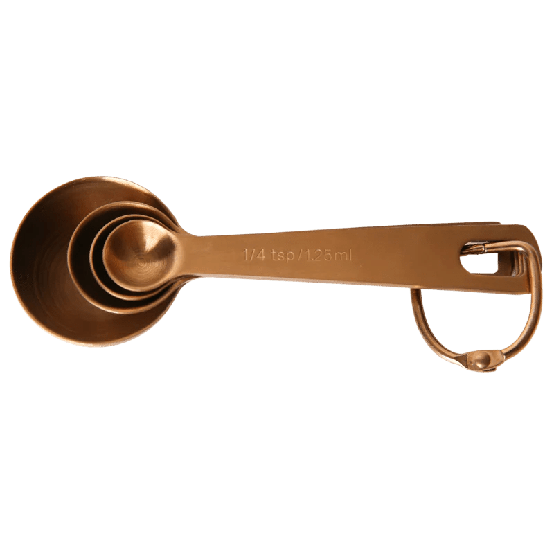 Seed & Sprout nesting metal measuring spoon set in a warm copper finish, neatly nested together and secured on a removable storage ring.