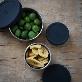 Seed & Sprout stainless steel nesting containers filled with green olives and banana chips.